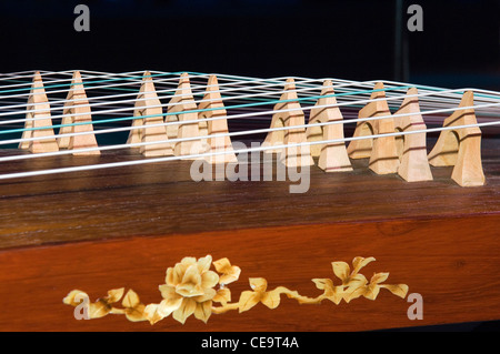 Chinois classique antique cithare musical instrument type la zheng, également connu sous le nom de guzheng. Détail des cordes et des ponts mobiles Banque D'Images