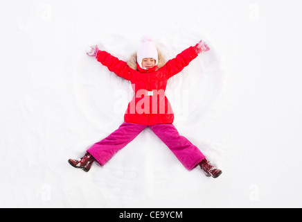 Jeune fille portant sur le terrain Making Snow Angel Banque D'Images