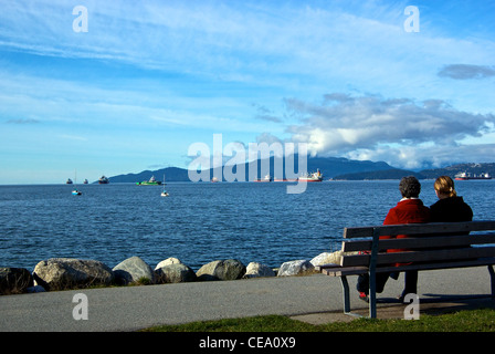 Deux femmes assises banc de parc Vanier Park à cargos ancrés English Bay Banque D'Images