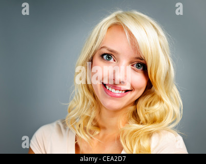 Portrait of smiling young blonde woman sur fond gris Banque D'Images