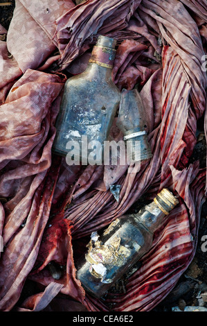 Verre bouteilles boissons whiskey jetés sur les déchets de matériel tissu dans la campagne indienne. L'Andhra Pradesh, Inde