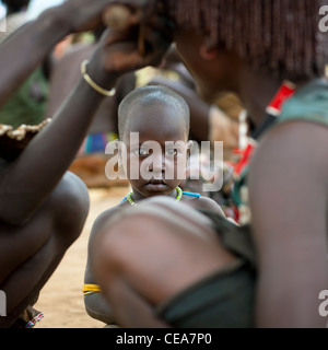 Bébé regardant Ochred Coupe de tresses de Femme Banna Ethiopie Banque D'Images