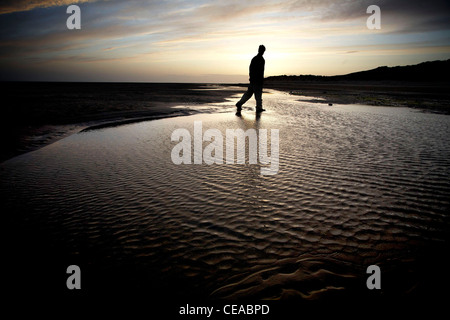Marcher dans l'eau de mer sur une plage de Barmouth Banque D'Images