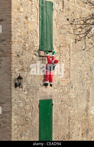 Père Noël gonflable escalade un mur, Italie Banque D'Images