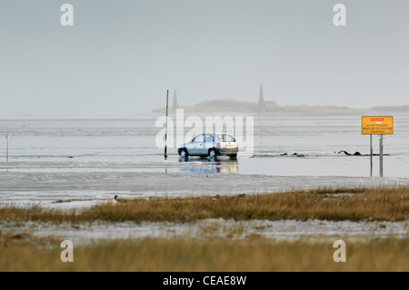 Car face à une marée montante de l'eau glacée sur le séisme causeway route menant à l'île de Lindisfarne (saint). La signalisation. Banque D'Images