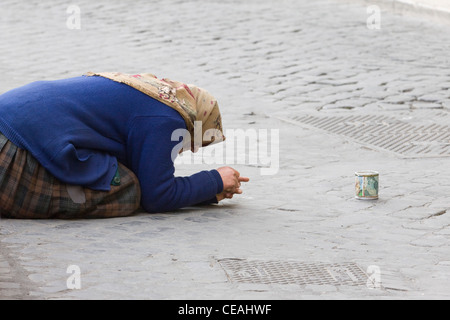 Une vieille dame mendier avec son fer-blanc sur les rues de Rome, Italie Banque D'Images