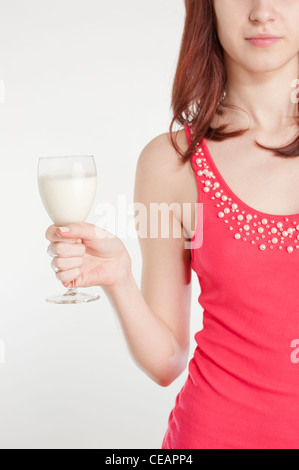 Jeune femme en robe rouge tenant un verre avec du lait Banque D'Images