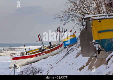 Bateaux de pêche sur une plage couverte de neige à Rewal, Pologne. L'hiver par la mer. Banque D'Images