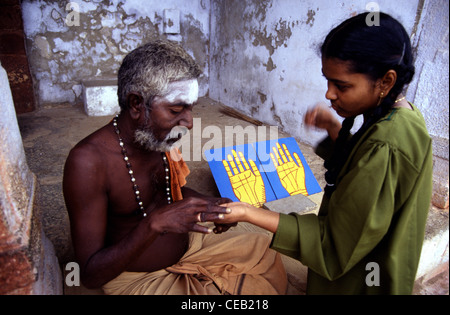 Fortune Teller qui tient la main d'une jeune femme pour palm reading dans le Tamil Nadu en Inde du Sud Banque D'Images