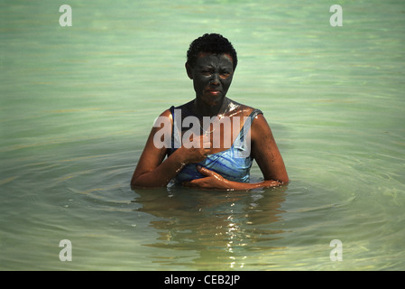 Un touriste d'Afrique enduite de natural boue noire de la mer morte baignade à la rive de la mer Morte en Israël Banque D'Images