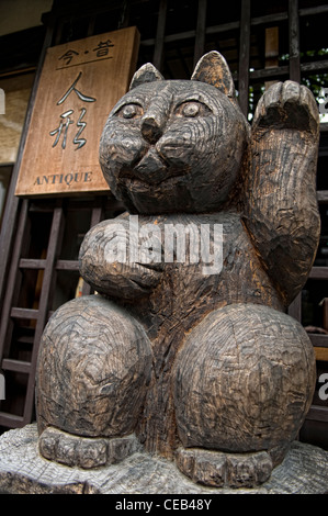 Un chat chanceux en bois sculpté (maneki neko) en face d'un magasin d'antiquités à Takayama Japon Banque D'Images