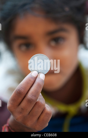 Jeunes pauvres caste inférieure Indian street girl holding a 2 rupee médaille. L'Andhra Pradesh, en Inde . Selective focus Banque D'Images