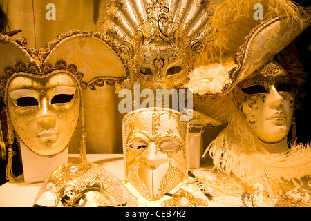 Venise, Vénétie, Italie. Les masques de carnaval d'or sur l'affichage en vitrine. Banque D'Images