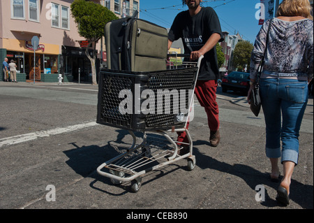 Jeune homme poussant un chariot de supermarché avec une valise battues à l'intérieur. Haight st. San Francisco USA Banque D'Images