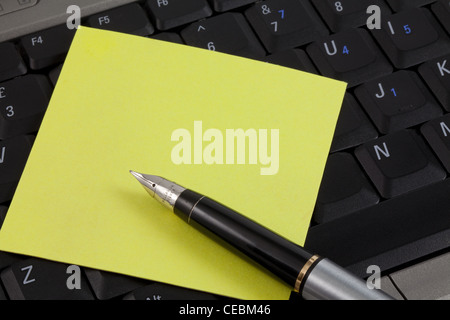 Un post-it jaune et un stylo sur un clavier d'ordinateur portable. Avec l'exemplaire de l'espace. Banque D'Images