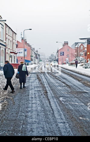 Une vieille dame passer à pied sur la route après les fortes chutes de neige dans la région de Lincoln, UK Banque D'Images