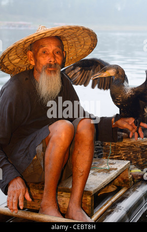 Le Cormorant fisherman holding bird sur un radeau de bambou sur la rivière li huangbutan chine Banque D'Images