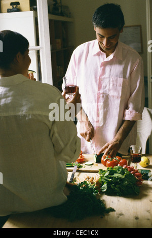 Woman watching man cutting vegetables in kitchen Banque D'Images