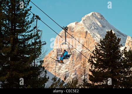 Skieurs sur une remontée mécanique avec Tofana di Rozes en arrière-plan, l'ascenseur de Faloria, Dolomites, Cortina d'Ampezzo, Italie ; Banque D'Images