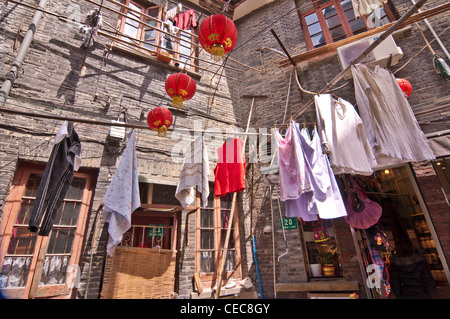 Un service de blanchisserie et de lampions suspendus dans une rue de Shanghai - Tianzifang, Taikang Lu, Shanghai - Chine Banque D'Images