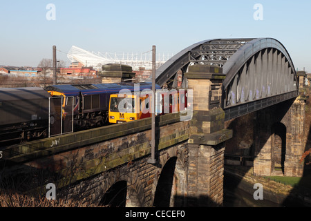 Un Tyne and Wear Metro train passe un train de charbon sur le pont ferroviaire de Wearmouth Sunderland North East England UK Banque D'Images