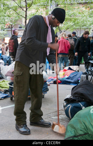 La ville de New York, Occupy Wall Street Protests à Zuccotti Park, également appelé Liberty Plaza, un homme balaie et nettoie le parc. Banque D'Images