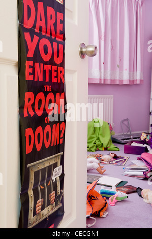 Porte de chambre à coucher poster (Dare vous entrez dans la chambre de doom ?) et l'enfant (fille), chambre en désordre encombré de jouets éparpillés - Yorkshire, Angleterre, Royaume-Uni Banque D'Images