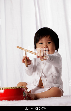 Bébé chinois avec des baguettes de tambour le tambour rouge holding Banque D'Images