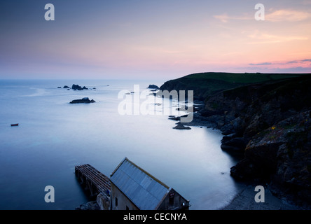 Vue sur la mer et d'un hangar à bateaux au coucher du soleil au lézard. Banque D'Images