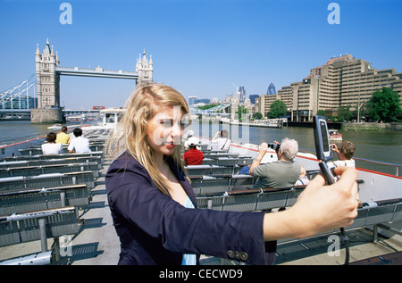 L'Angleterre, Londres, Woman Taking Photograph with Camera Phone on Boat Banque D'Images