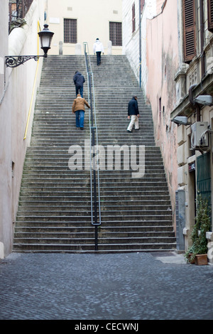 Quatre hommes escalade un escalier en pierre très raide à Roma Italie Banque D'Images