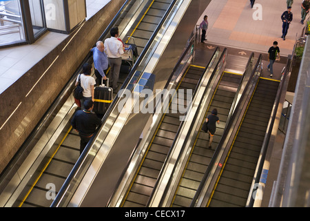 Les gens monter un tapis roulant à l'aéroport de Changi à Singapour Banque D'Images