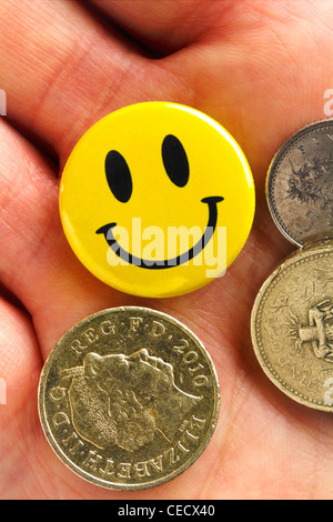 Badge smiley dans la paume de la main avec la monnaie. Banque D'Images