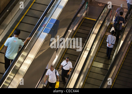 Les gens monter un tapis roulant à l'aéroport de Changi à Singapour Banque D'Images