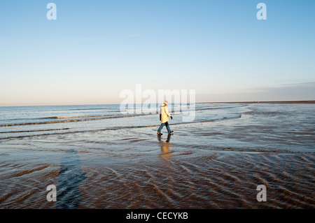 Middle aged woman walking on the beach le chemin côtier, Norfolk Norfolk, England, UK Banque D'Images