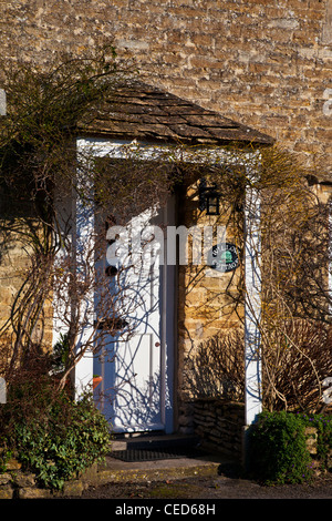 Porche à pignons et blanc avant porte d'un chalet typique en pierre de Cotswold en hiver. Banque D'Images