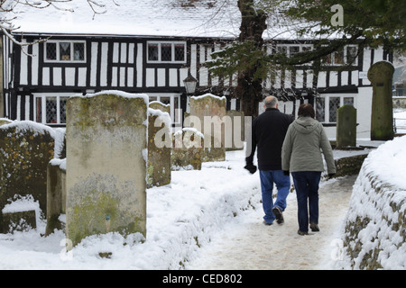 Deux personnes couple mari et femme et marcher dans un cimetière en hiver neige neigeux Vieille Ville Eastbourne, East Sussex, Angleterre Banque D'Images