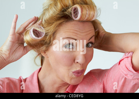 Caucasian woman mettre les rouleaux dans les cheveux Banque D'Images