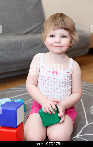 Portrait de petite fille jouant avec des briques sur marbre Banque D'Images