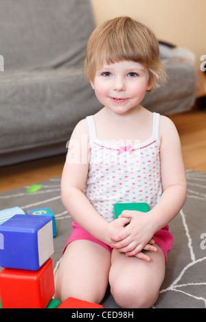 Portrait de petite fille jouant avec des briques sur marbre Banque D'Images