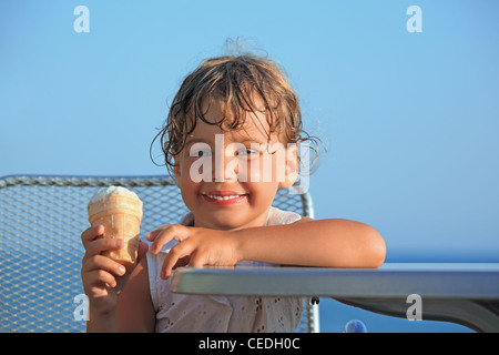 Smiling little girl mange des glaces à resort Banque D'Images