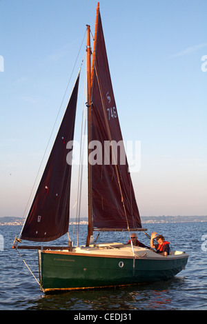 Couple mature naviguant Cornish Shrimper bateau dans le port de Poole à Poole, Dorset Royaume-Uni en juillet Banque D'Images