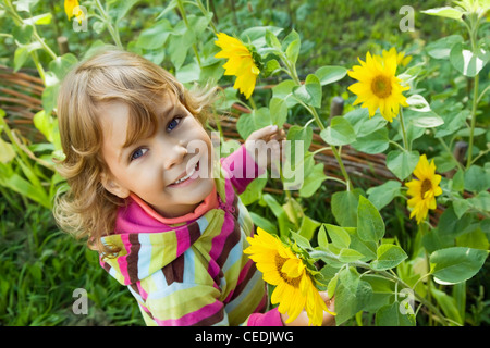 Jolie petite fille tient dans la main de tournesol dans jardin Banque D'Images