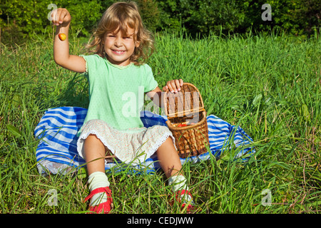 Jolie petite fille tient dans la main la cerise douce au jardin Banque D'Images