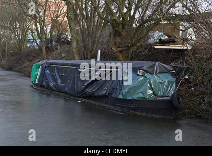 Bateau étroit canal recouvert de bâches de protection sur un canal gelé Banque D'Images