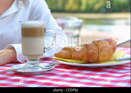 France, la femme à cafe latte et un croissant sur la table Banque D'Images