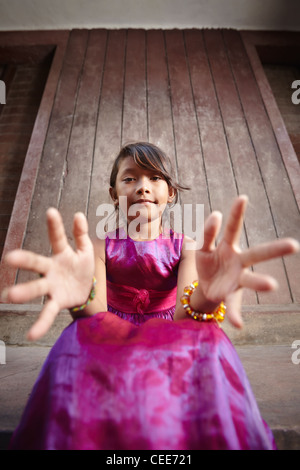 Portrait of cute Asian female enfant en robe rose pointant mains at camera Banque D'Images