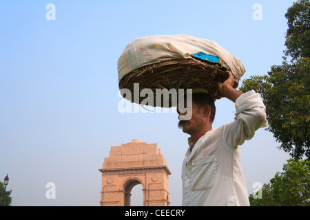 Indian man carrying basket sur tête, Indian Gate dans la distance, Delhi, Inde Banque D'Images
