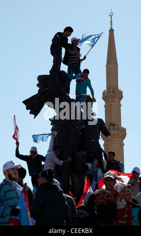 Partisans politiques avec les drapeaux escalader Place des Martyrs monument à Beyrouth, au Liban. Minaret en arrière-plan Banque D'Images