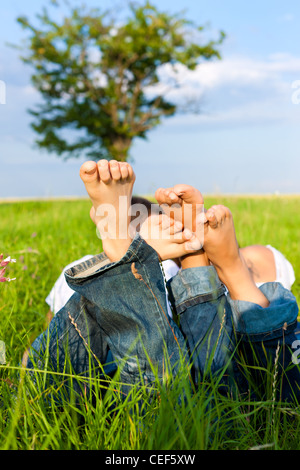 Heureux couple allongé sur un pré en été, pieds seulement d'être vu Banque D'Images